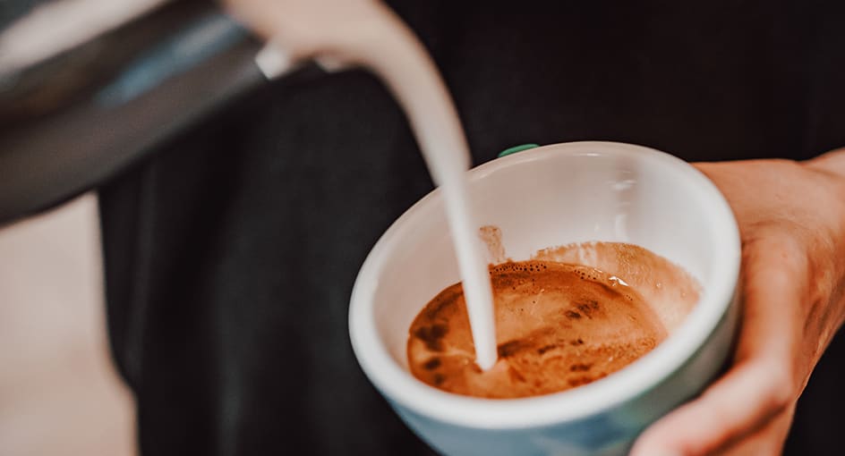 Close-up of milk being poured into a cup of coffee
