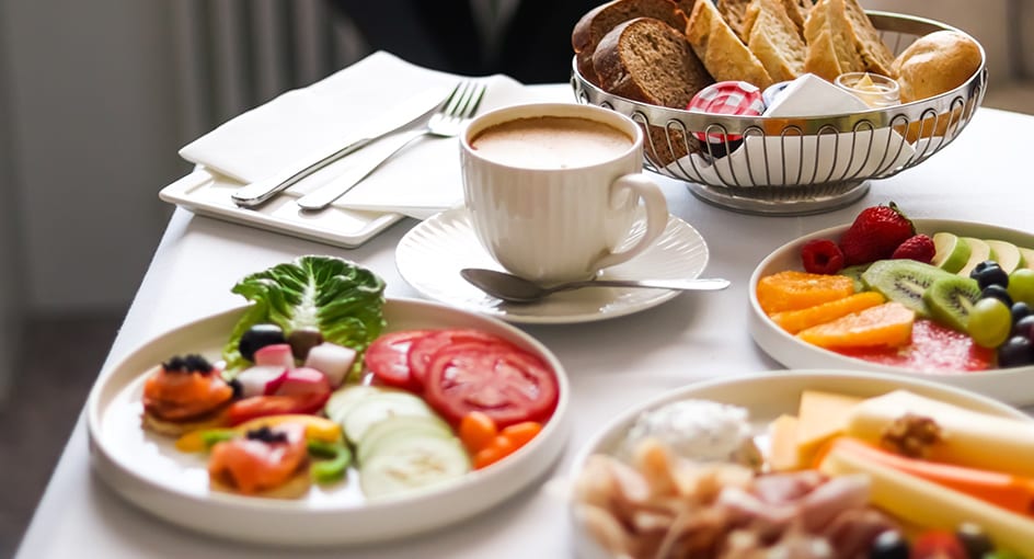 In-room dining breakfast spread with coffee, fresh fruits, bread, and salad