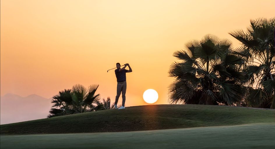 Golfer silhouetted at sunrise on golf course at Tivoli LA VIE Muscat Hotel 