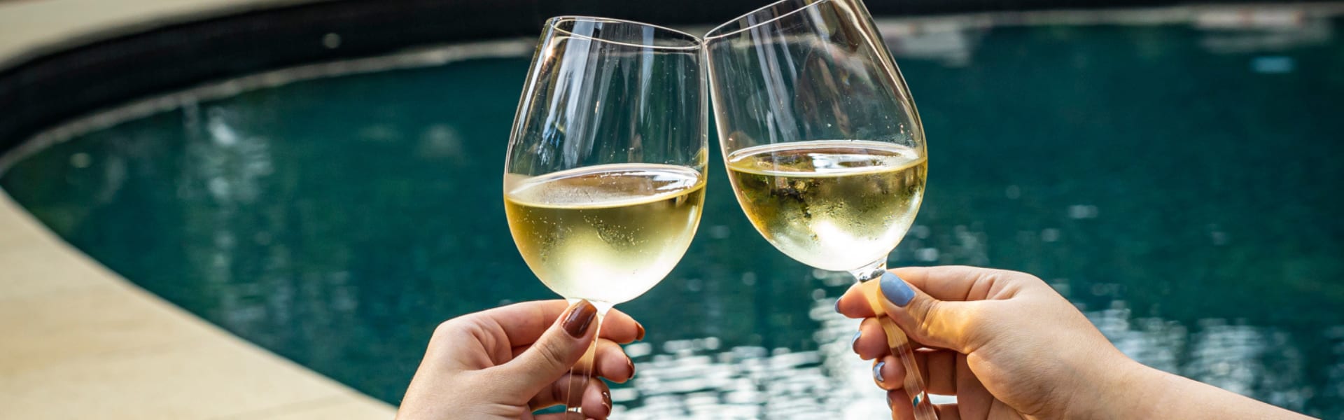 Brinde com duas taças de vinho branco em frente à piscina do hotel Tivoli Mofarrej São Paulo