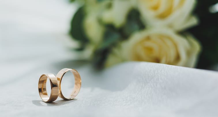 Two gold wedding bands resting on a white fabric surface