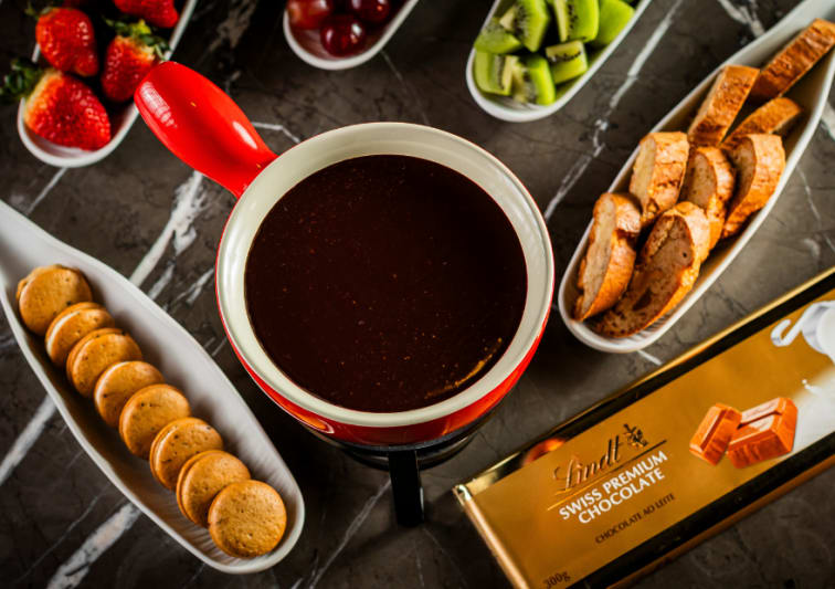 Fondue de chocolate Lindt, com uvas, kiwi, morangos e biscoitos.