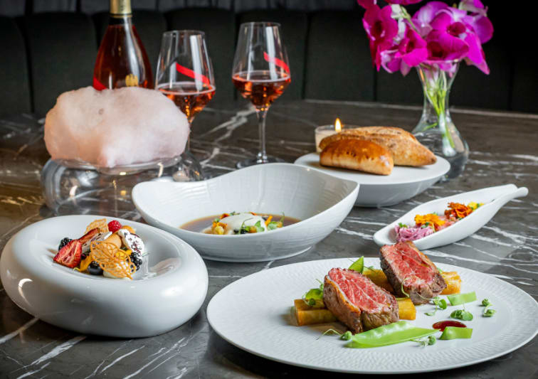 Mesa posta do jantar de namorados do Must Restaurant, com prato de carne, sobremesas , entrada, vinhos, vaso de flor