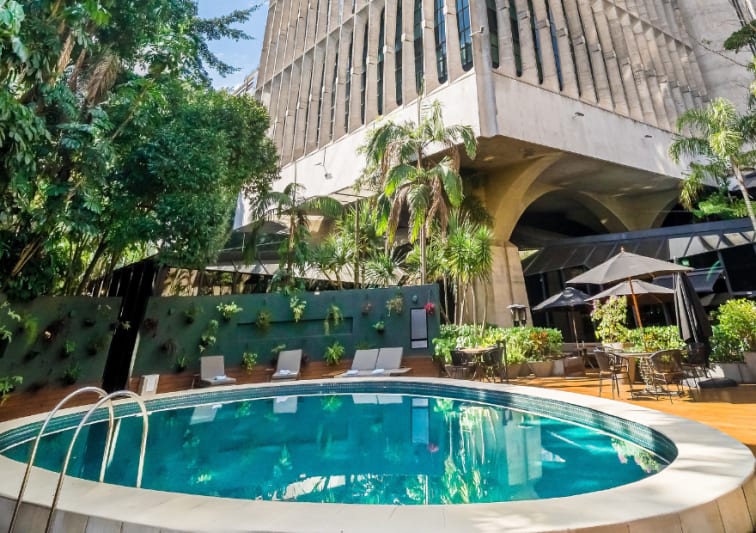 Piscina do hotel Tivoli Mofarrej, com visto do prédio atrás, e jardim ao redor